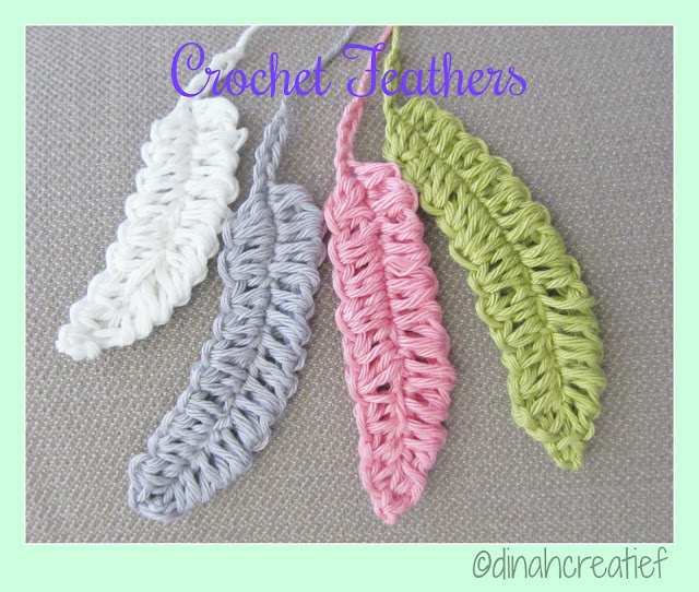 Four crochet feathers in white, gray, pink, and green are displayed on a textured beige surface. The text Crochet Feather appears at the top, with @dinahcreatief in the bottom right corner.