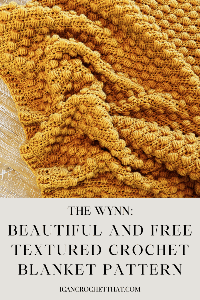 A mustard yellow textured crochet blanket is displayed on a wooden surface. Text below reads: The Wynn: Beautiful and Free textured crochet blanket pattern.