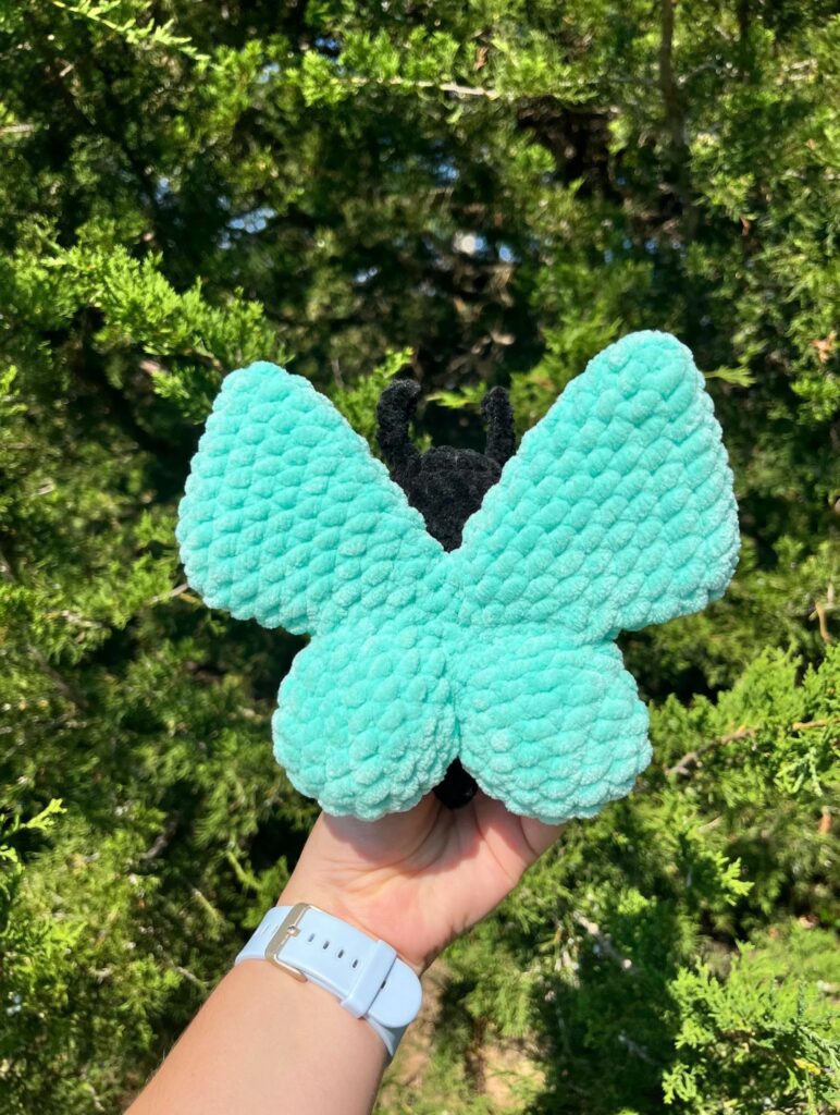 Soft, handmade butterfly amigurumi in pastel yarn colors.