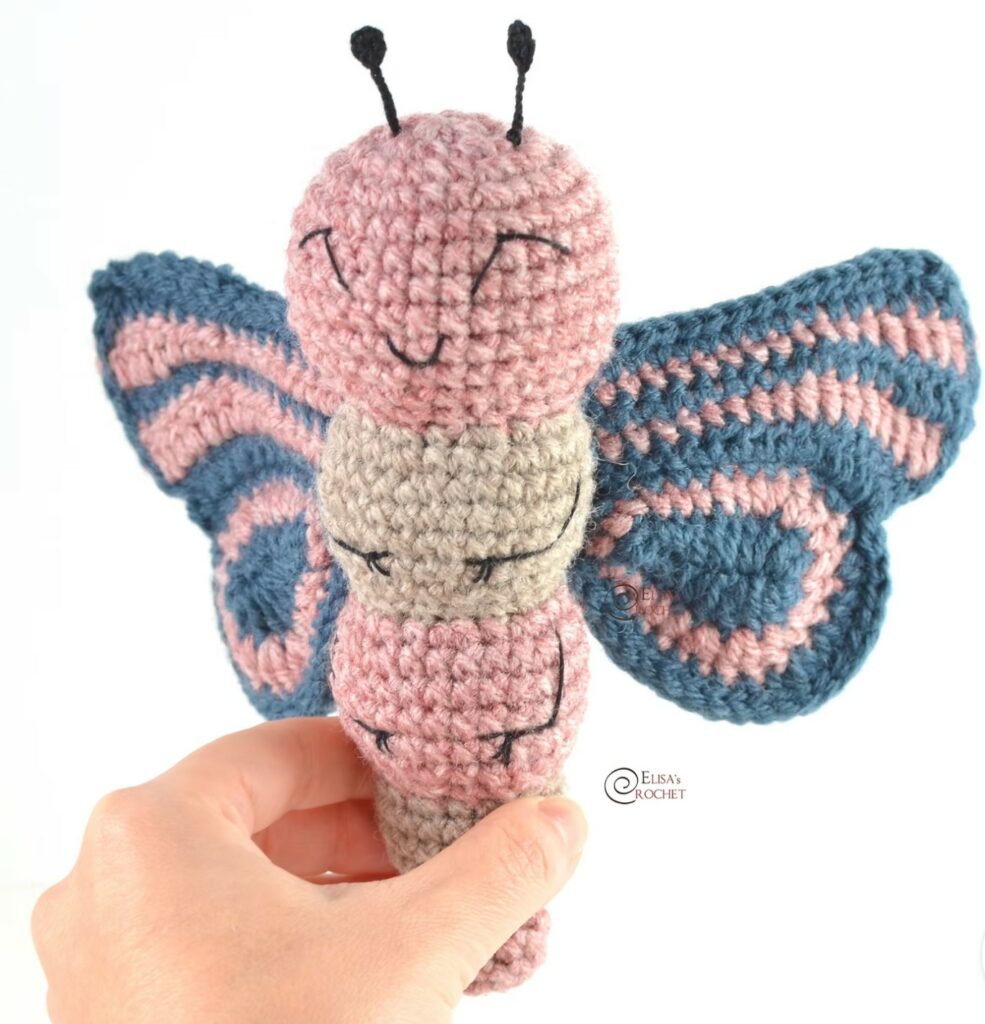 Soft, handmade butterfly amigurumi in pastel yarn colors.