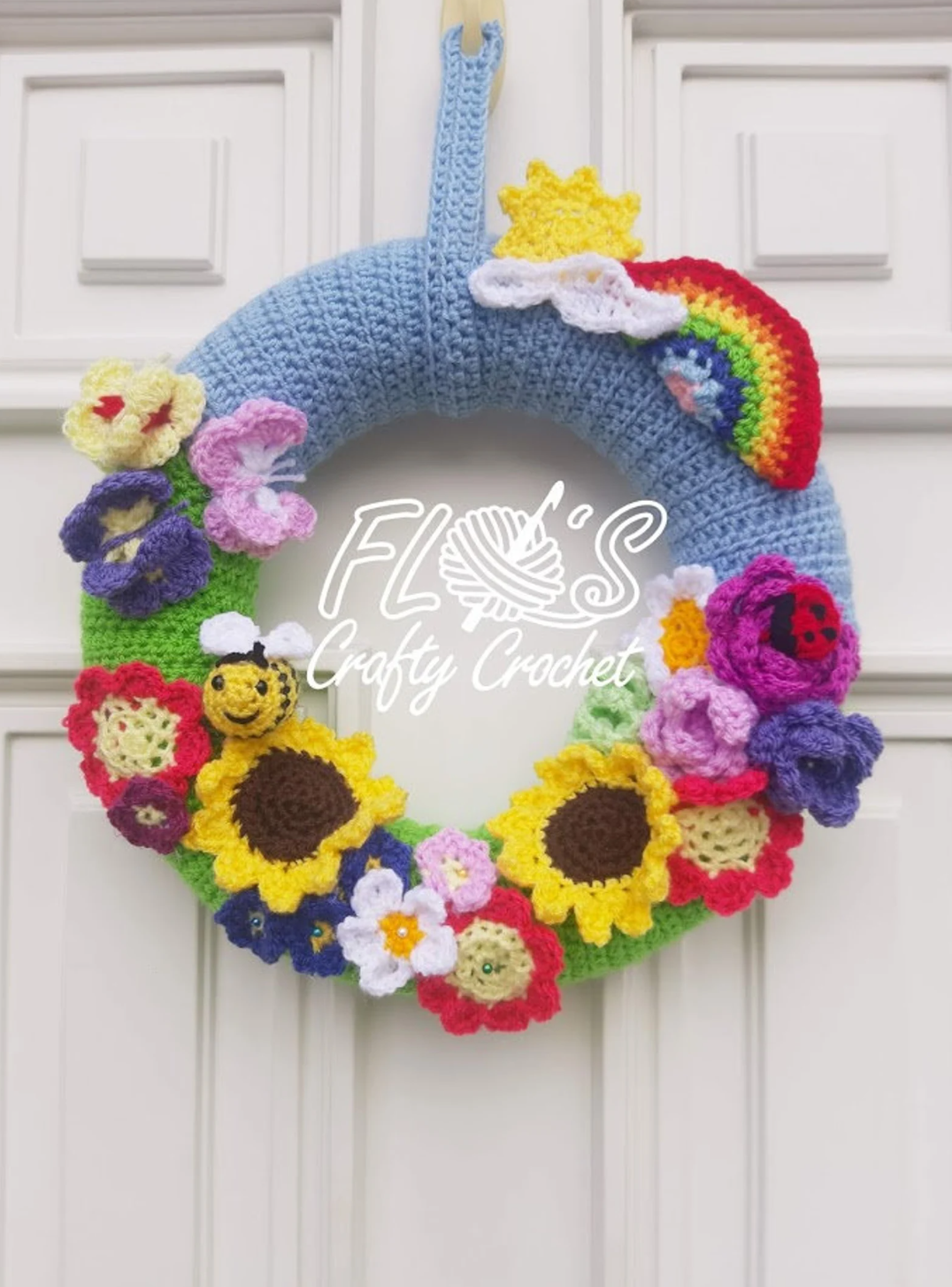 Detailed view of a handmade crochet flower wreath hanging on a front door, styled with summer blooms and textures.