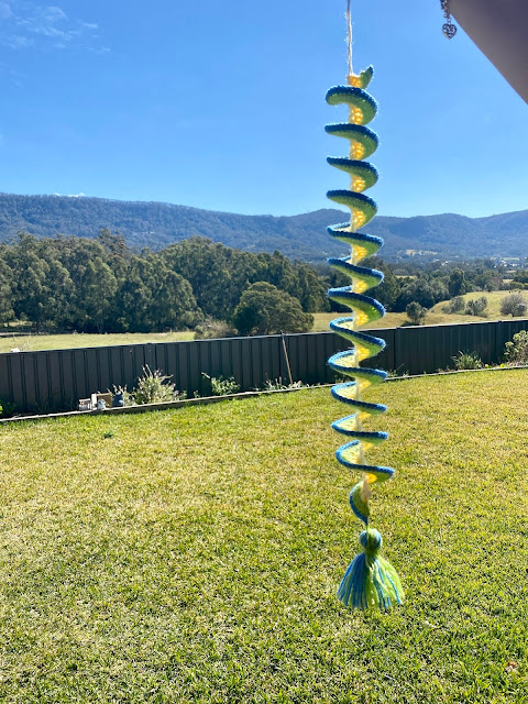 Close-up of a handmade crochet wind spinner with bright colors and spiral shape.