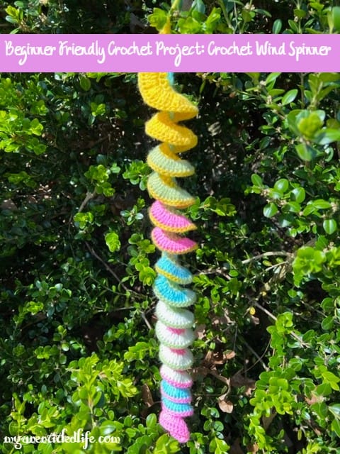 Close-up of a handmade crochet wind spinner with bright colors and spiral shape.