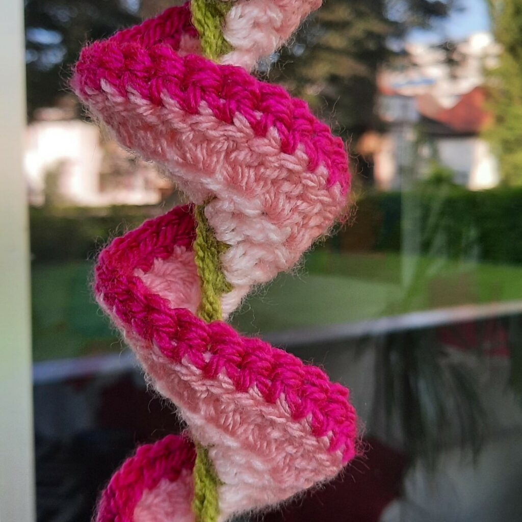 Vibrant crochet wind spinners displayed in a garden, swaying gently in the wind.