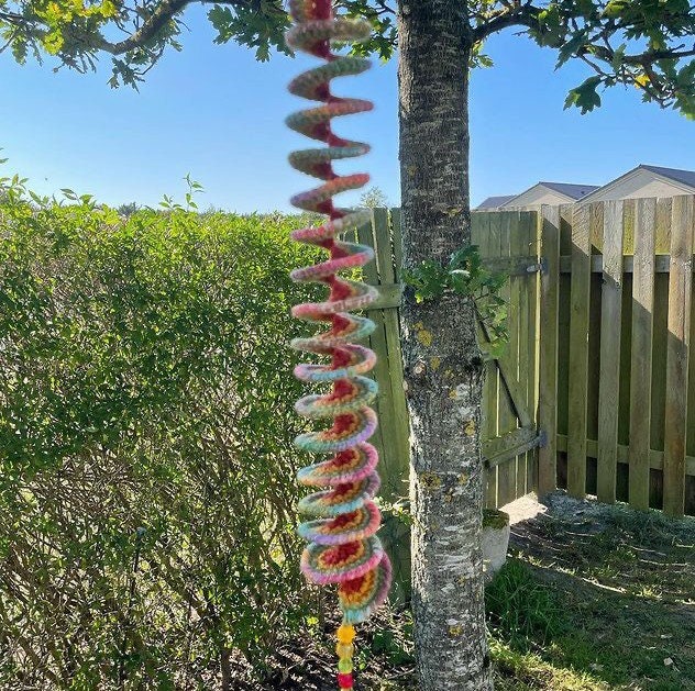 Vibrant crochet wind spinners displayed in a garden, swaying gently in the wind.