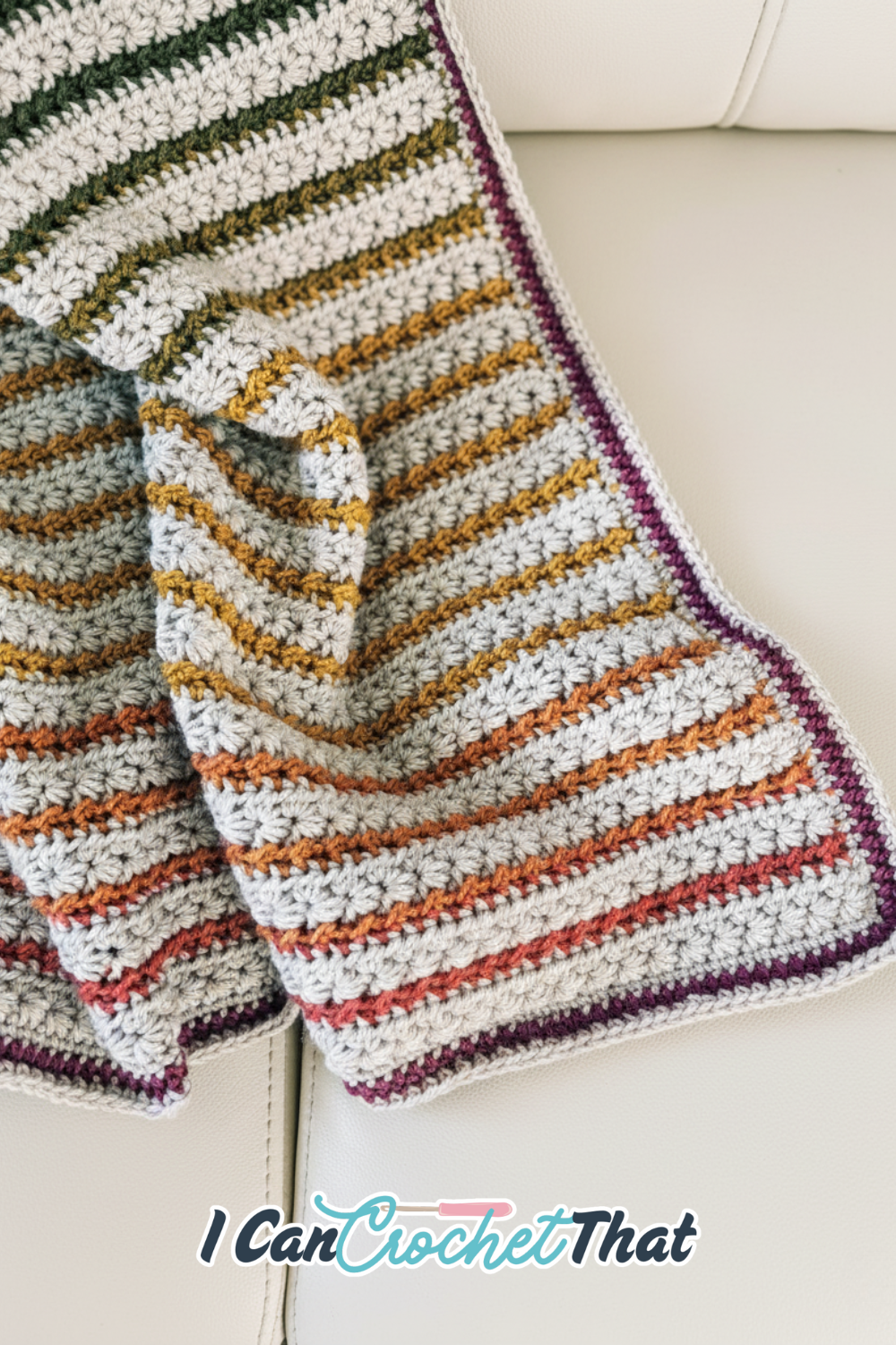 Textured crochet blanket draped over a chair, featuring cream yarn and colorful star stitch stripes.
