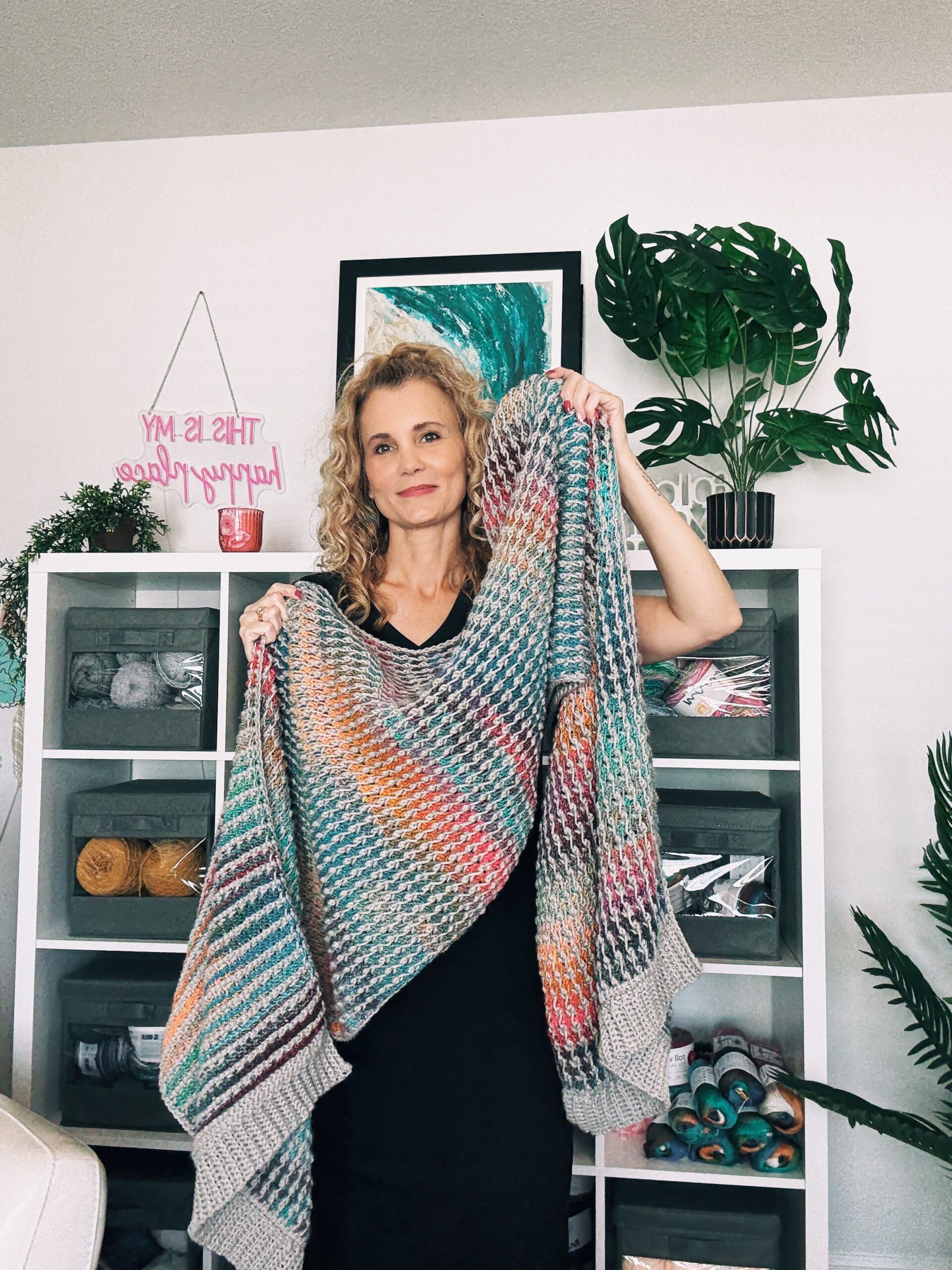 Close-up of a gray and multicolor Tunisian crochet blanket scarf made with the field stitch, showing rich woven texture.