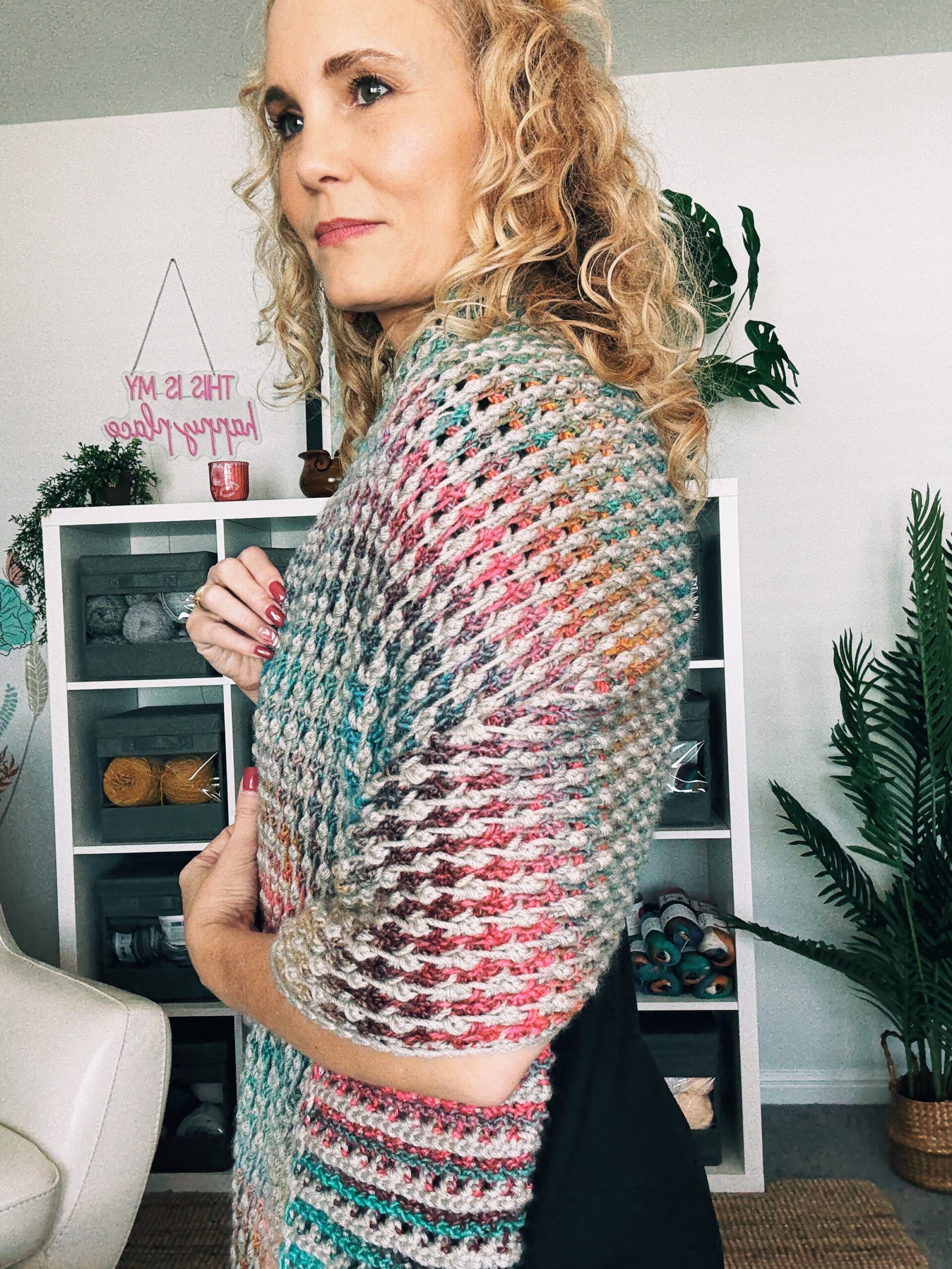 Woman wearing the Tunisian Field Stitch Blanket Scarf in gray and multicolor yarn.