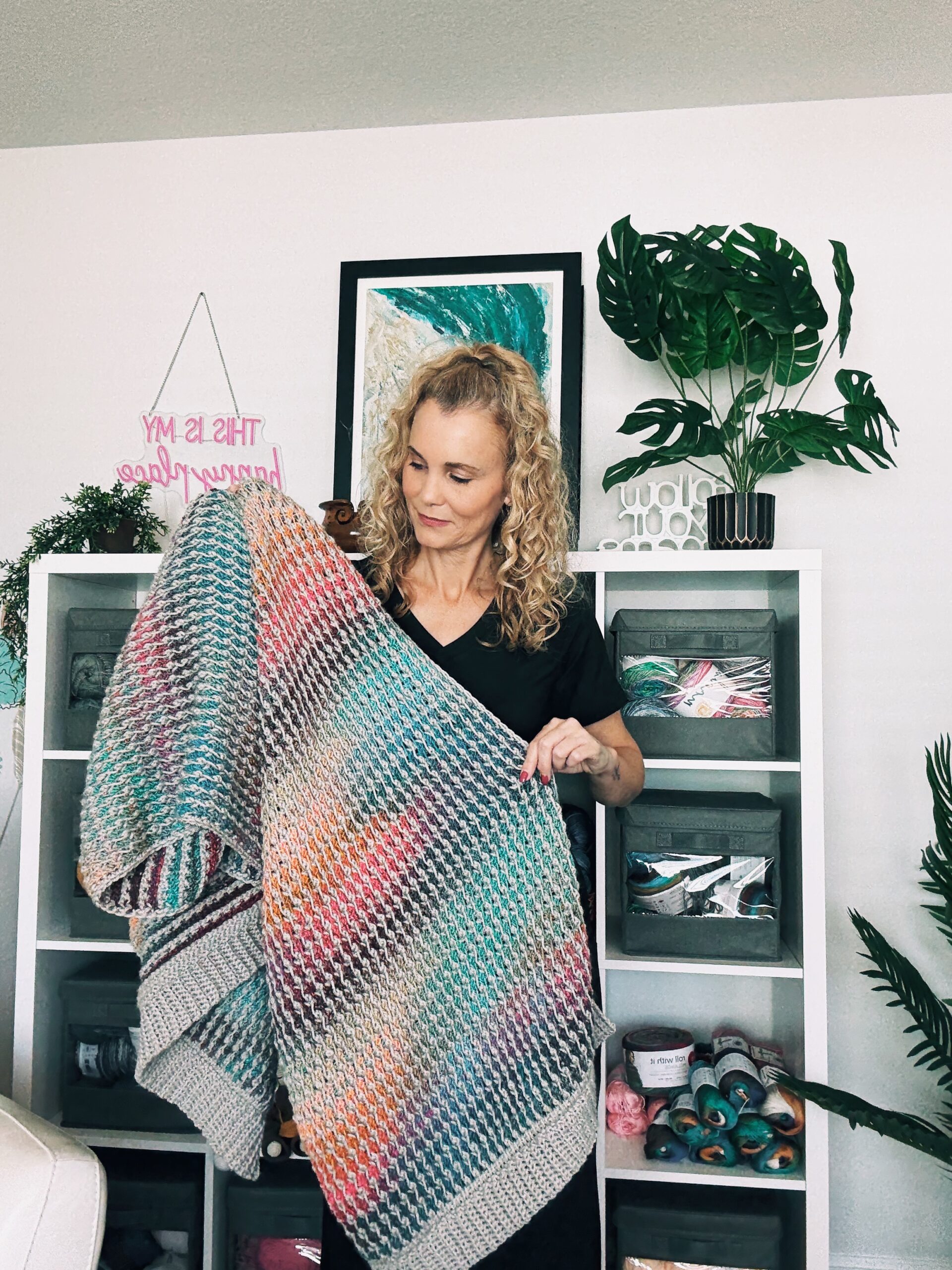 Tunisian crochet field stitch blanket scarf draped over a chair, highlighting its ribbed border and woven texture.