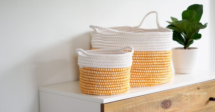 Two woven baskets with white and yellow stripes sit on a white dresser next to a potted plant against a plain white wall.