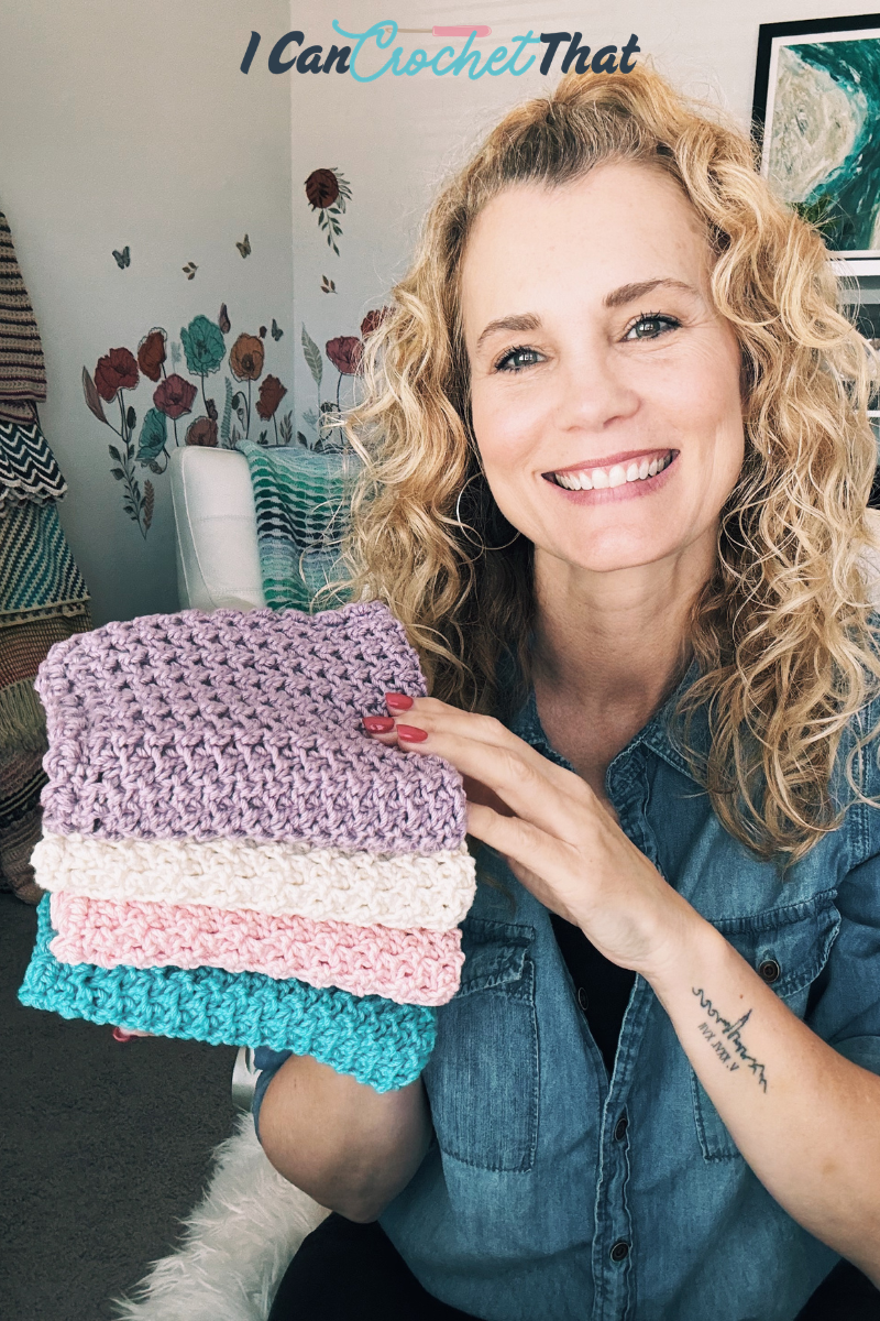 A woman with curly blonde hair holds up four crocheted washcloths in different colors while smiling at the camera. The words I Can Crochet That appear above her head.