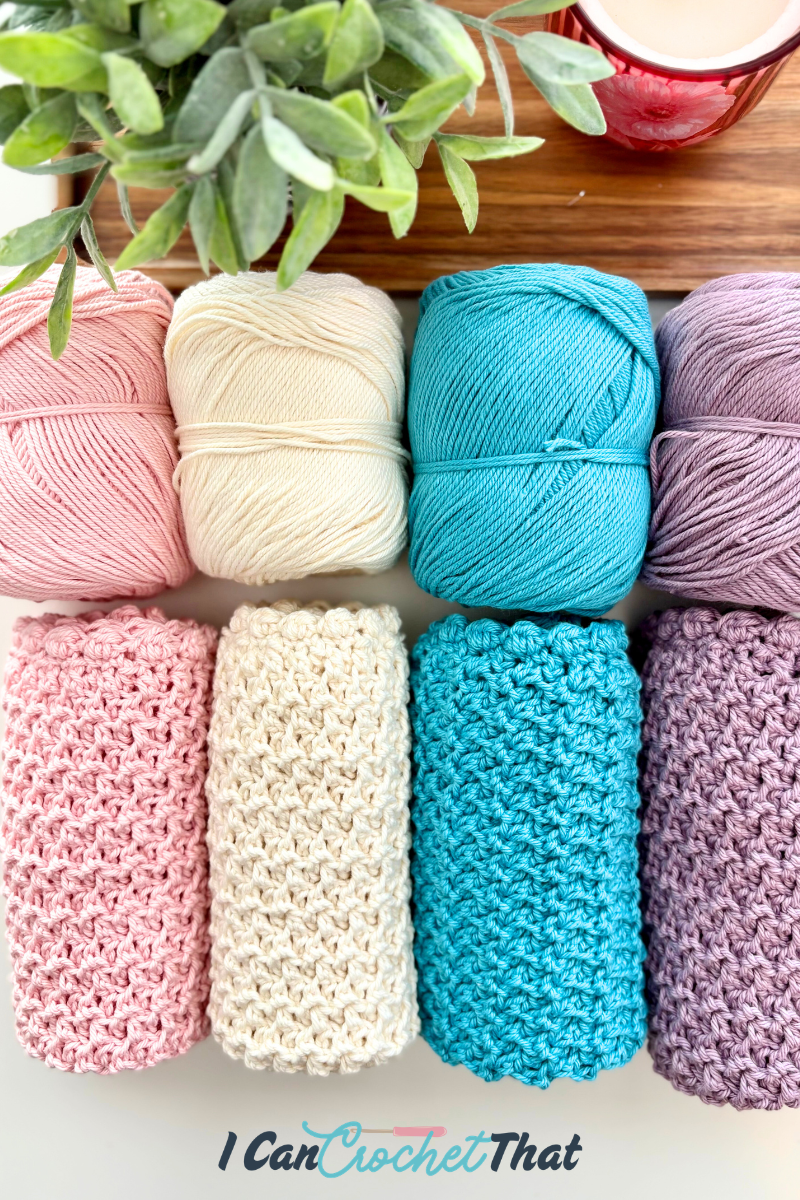 Four skeins of yarn and four crocheted swatches in coordinating pastel colors are arranged neatly on a white surface next to a plant and a mug.